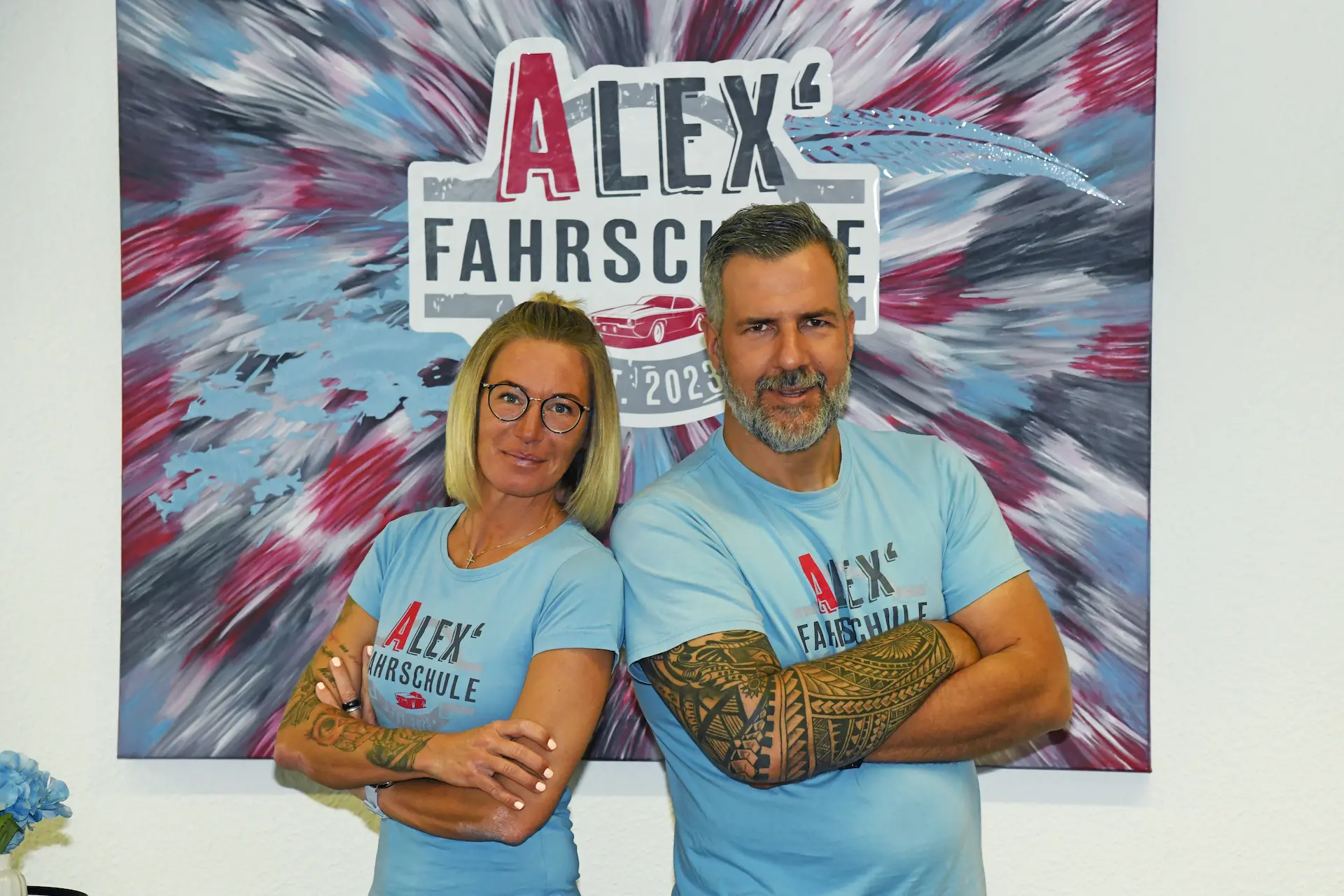 Die führenden Köpfe von "Alex´ Fahrschule": Alex und Caro vor Ihrem Logo